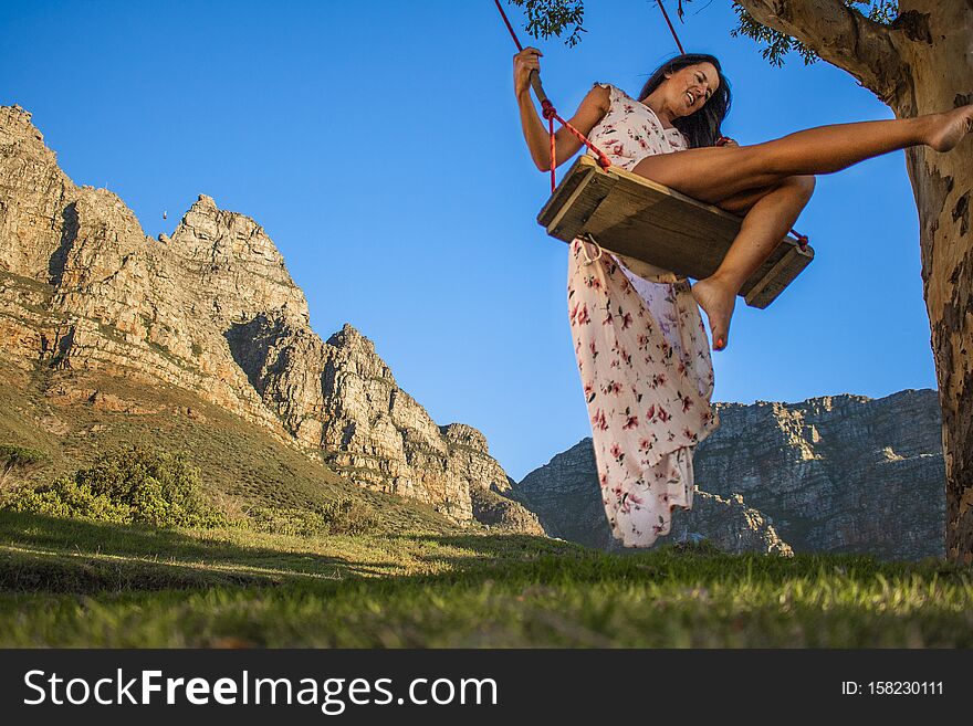 Beautiful Woman Swinging On A Swing In Nature With Table Mountain In The Background.