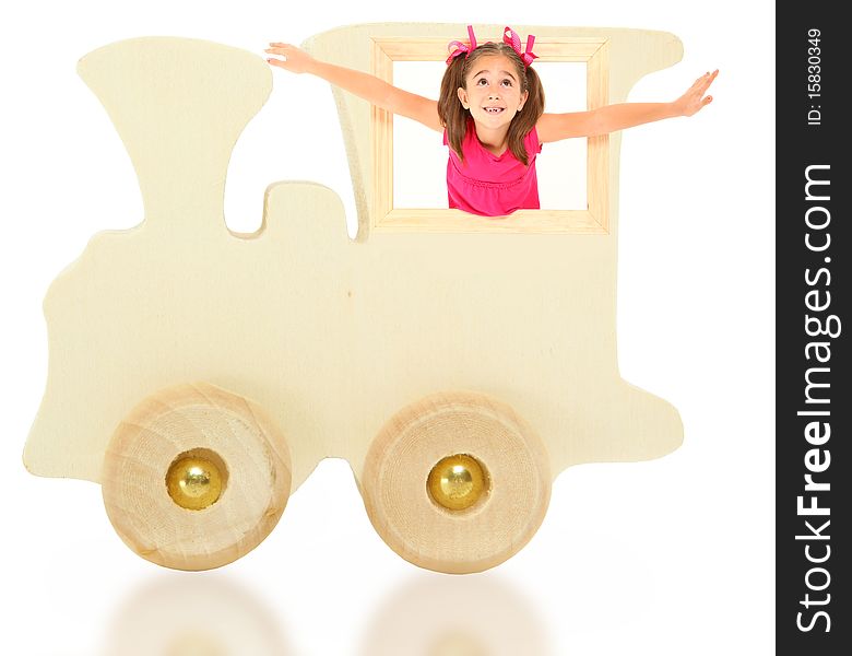 Beautiful 7 year old american girl riding in wooden toy train engine over white background with reflection. Beautiful 7 year old american girl riding in wooden toy train engine over white background with reflection.