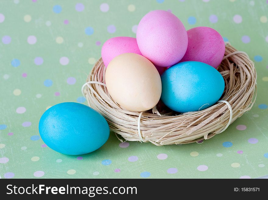 Colorful eggs in the nest on polka dot background