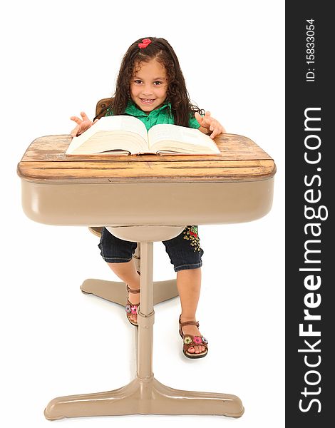 Happy three year old hispanic girl sitting in school desk over white background. Happy three year old hispanic girl sitting in school desk over white background.