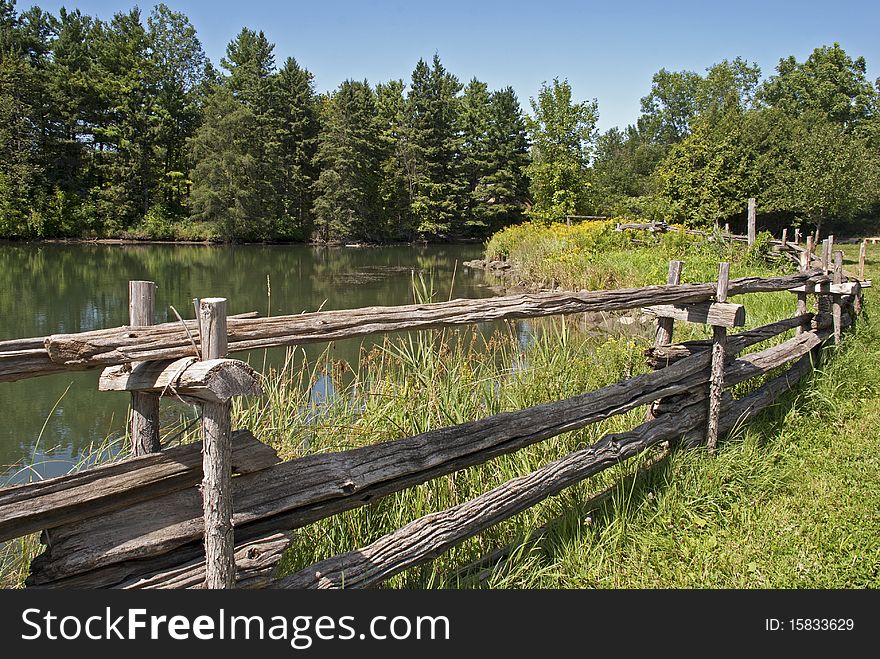 Summer landscape in rural Eastern Canada with pond and old fence. Summer landscape in rural Eastern Canada with pond and old fence