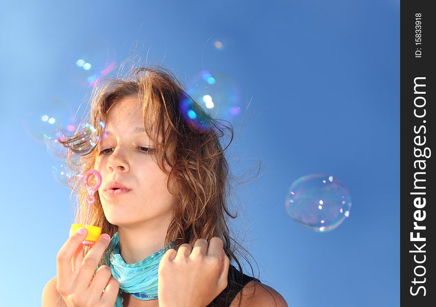 Girl on a beach inflates soap bubbles