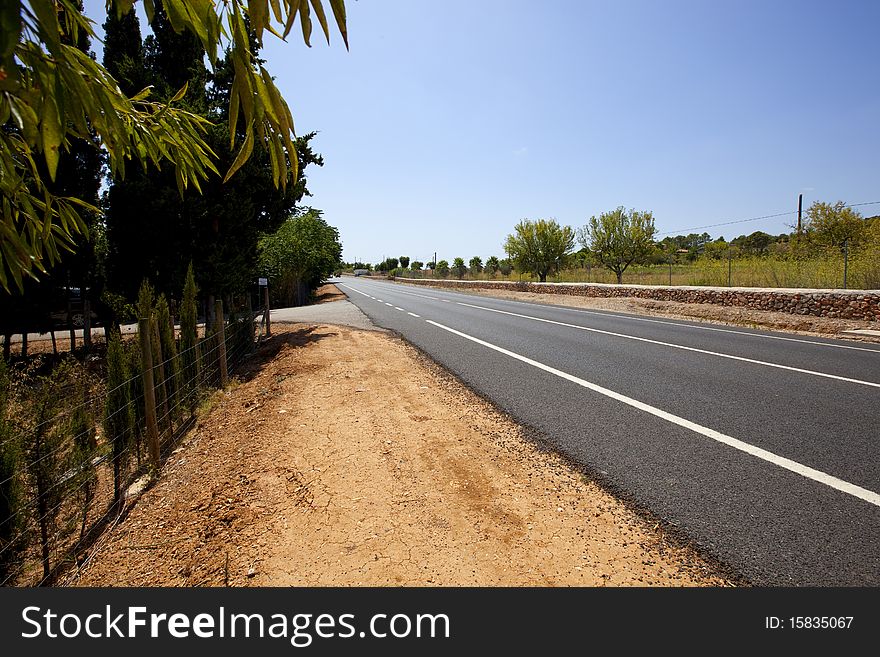 Highway road across non-urban summer landscape with blue sky and clouds. Highway road across non-urban summer landscape with blue sky and clouds