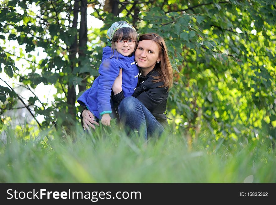 Adorable young mother and daughter in warm coats on green background. Adorable young mother and daughter in warm coats on green background