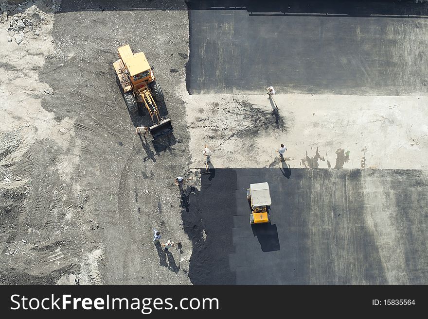 Workers repairing the road using road roller and excavator