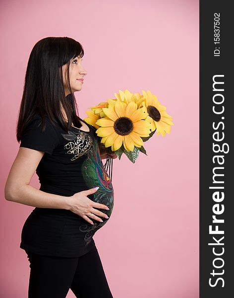 Beautiful pregnant woman holding belly with flowers, Studio