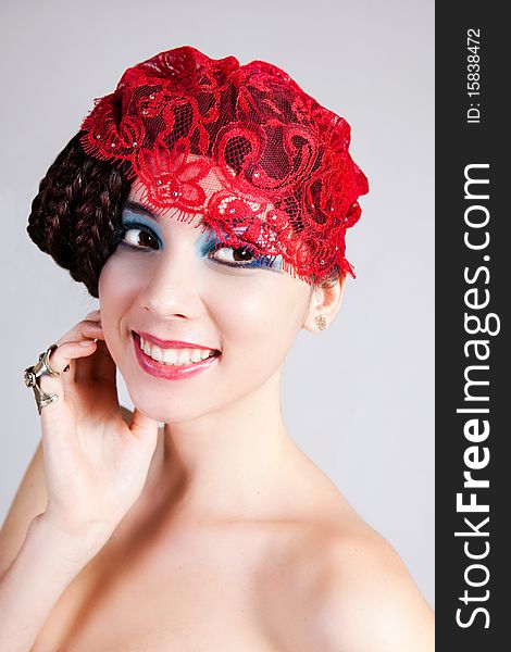 A glamorous, high fashion woman smiles to the side while posing with red lace headpiece on her head and bare shoulders. Vertical shot. A glamorous, high fashion woman smiles to the side while posing with red lace headpiece on her head and bare shoulders. Vertical shot.