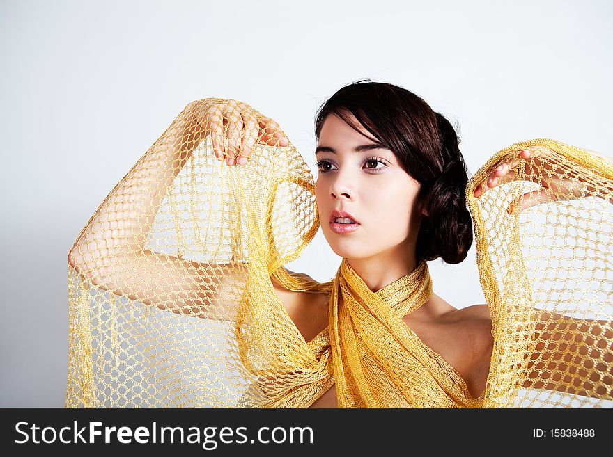 A glamorous, high fashion woman looks to the side while posing in a yellow mesh wrap. Horizontal shot. A glamorous, high fashion woman looks to the side while posing in a yellow mesh wrap. Horizontal shot.