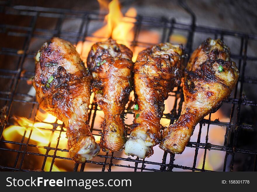 Grilled chicken legs barbecue with herbs and spices top view - Tasty chicken legs on the grill with fire flames marinated with