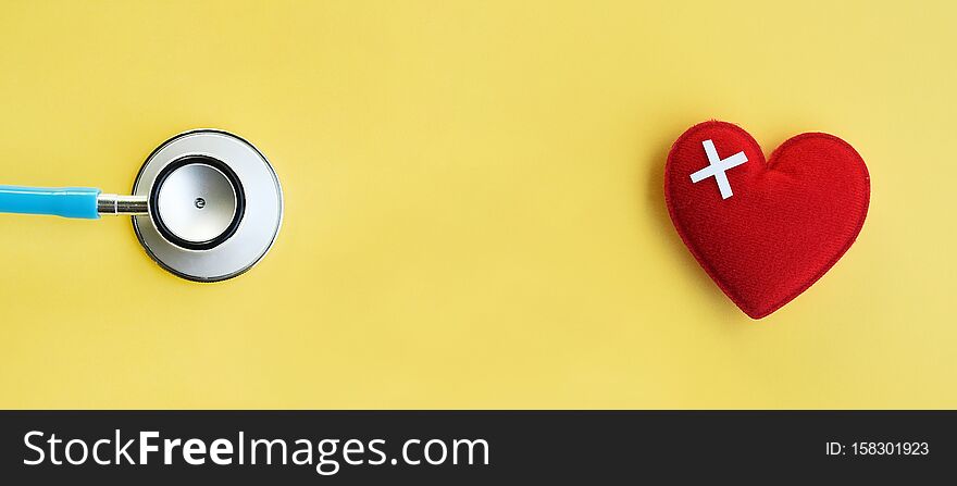 Red heart with stethoscope on yellow background