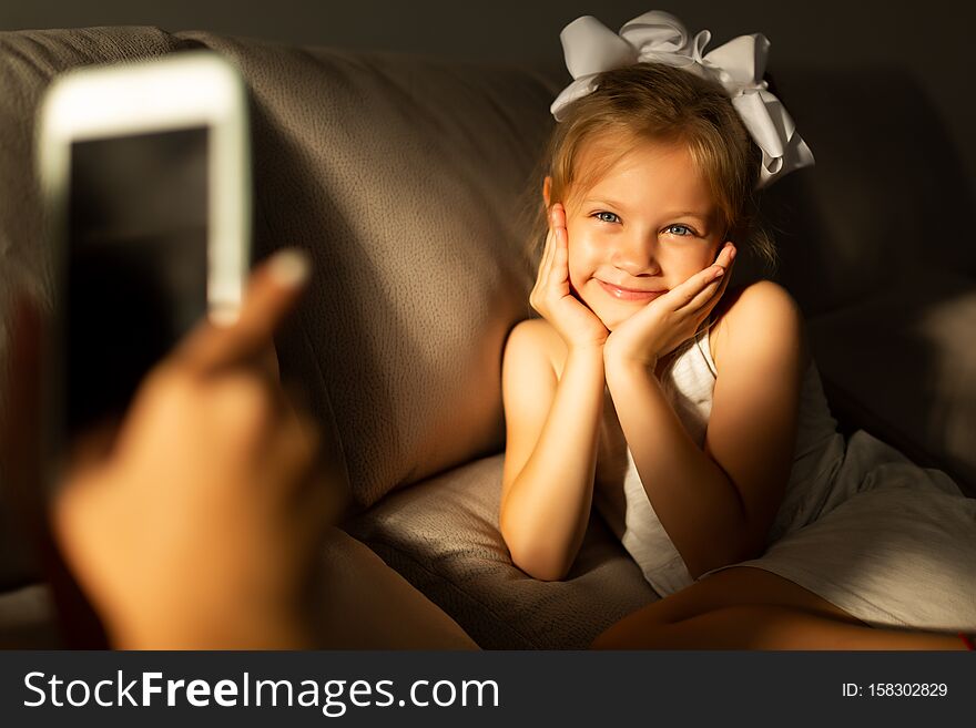 Mom takes a picture of her daughter using a phone in low light.