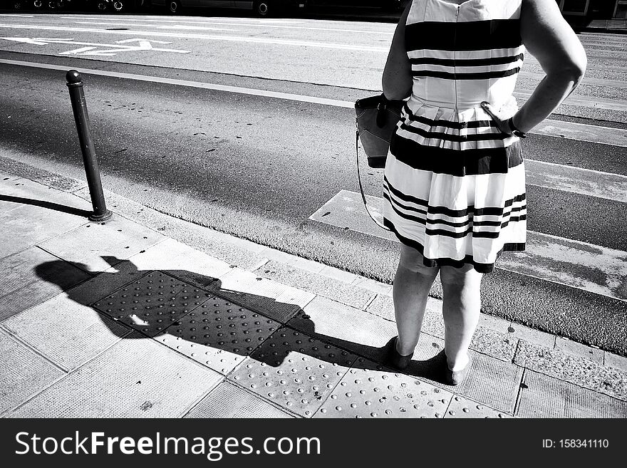 Street photography with woman on the sidewalk in Geneva city, Switzerland. Black and white image.