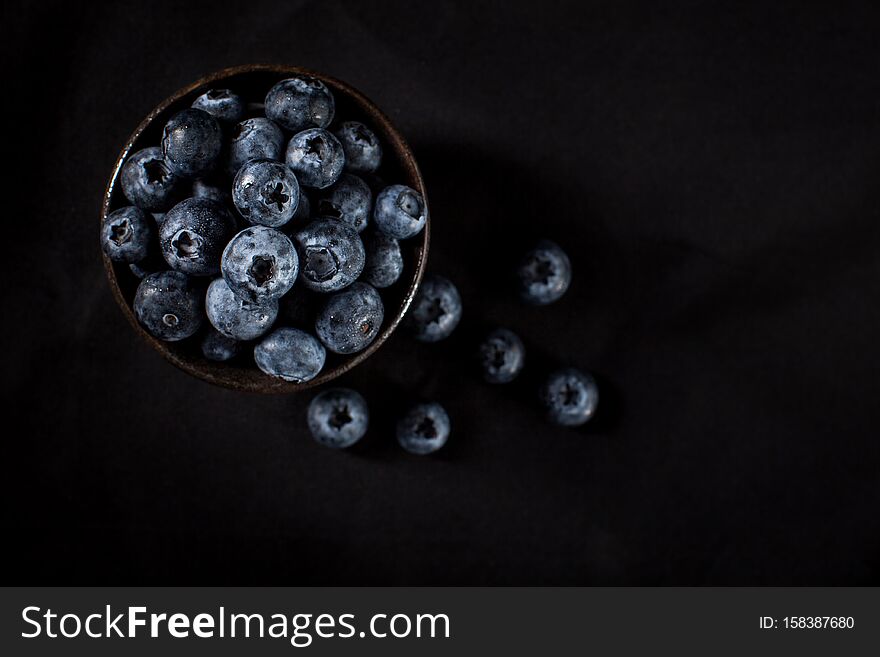 Blueberries In A Brown Ceramic Bowl Placed On A Black