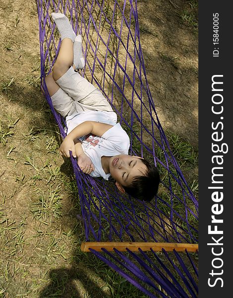 Picture of a little chinese boy sleeping in hammock and enjoying autumn breeze and sunshine