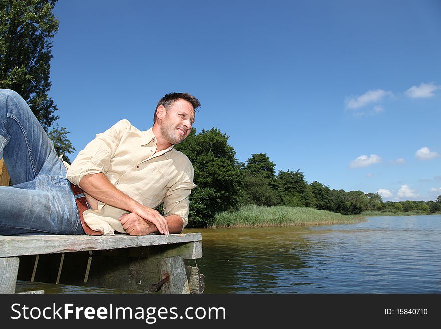 Man resting on a pontoon by a lake. Man resting on a pontoon by a lake
