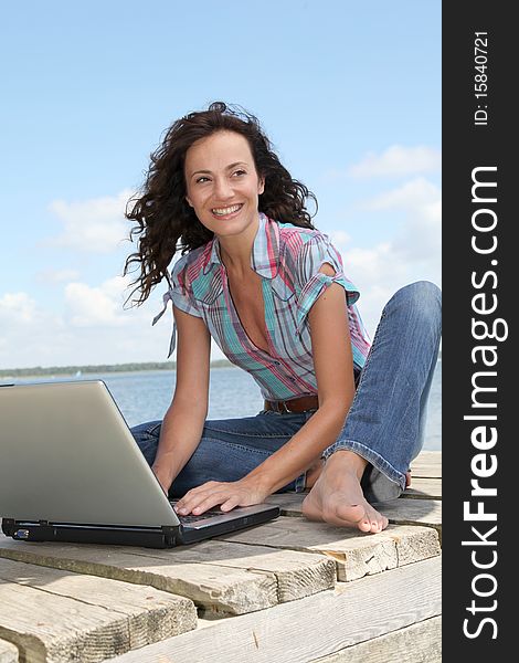 Woman using laptop computer on a pontoon. Woman using laptop computer on a pontoon