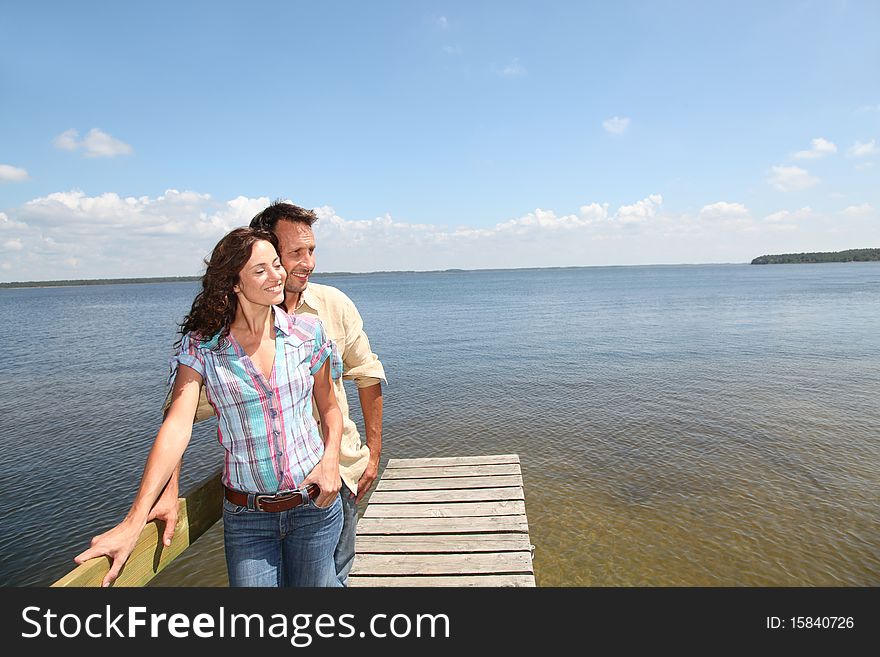 Loving couple standing on a pontoon by a lake. Loving couple standing on a pontoon by a lake