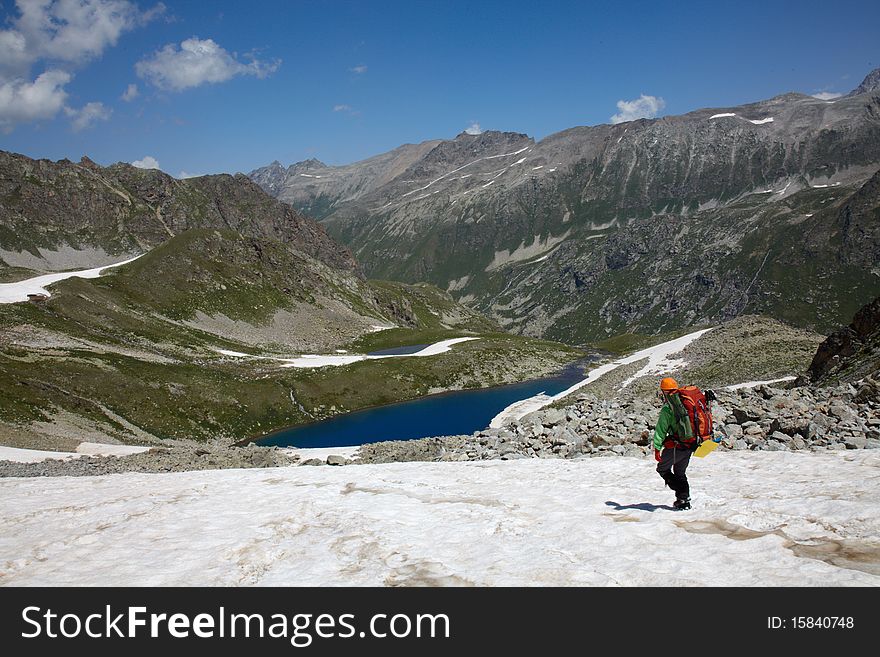 Backpacker walking down to mountain lake. Backpacker walking down to mountain lake