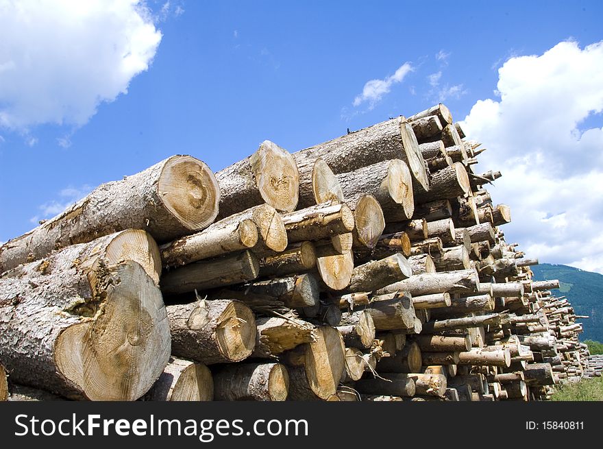 Shot of woodpile beyond blue cloudy sky.