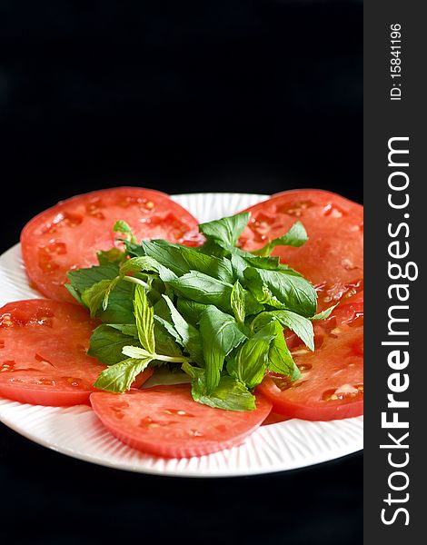 Tomato slices on a white plate isolated on black background