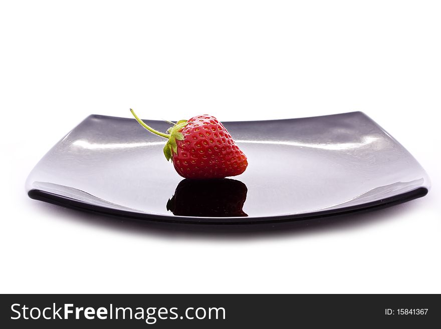 Red strawberry on black plate isolated on white