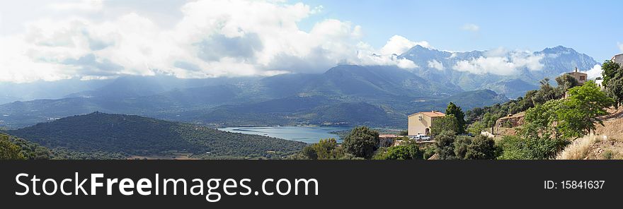 Panoramic view of villa in Corsica with mountains and lake in background. Panoramic view of villa in Corsica with mountains and lake in background