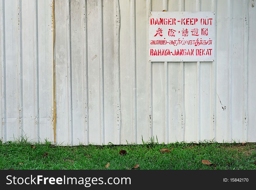 Danger signboard on white fence