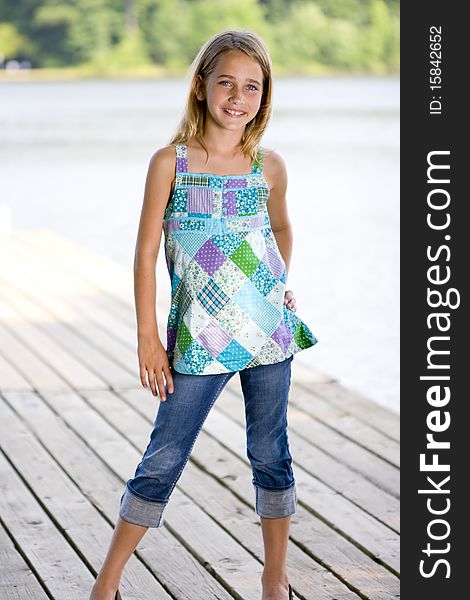 A young, pretty, preadolescent girl standing on a dock and smiling at the camera. A young, pretty, preadolescent girl standing on a dock and smiling at the camera.