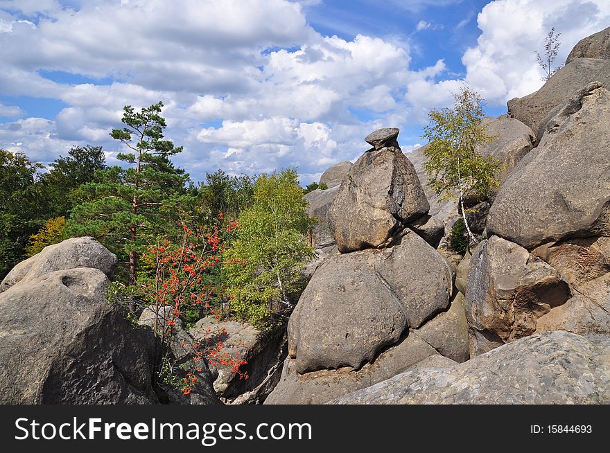 Rocks over wood in an autumn mountain landscape under the dark blue sky. Rocks over wood in an autumn mountain landscape under the dark blue sky