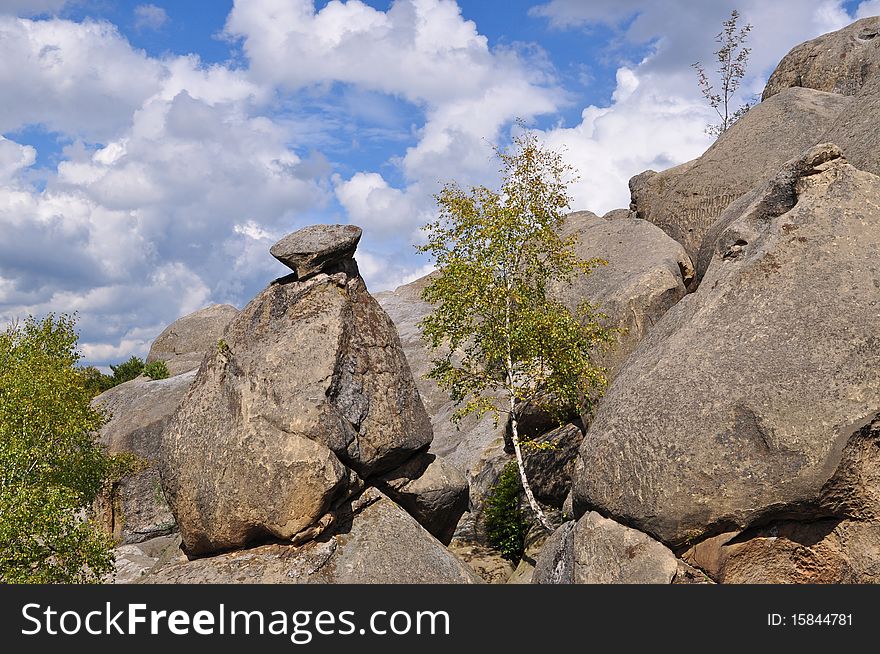 Rocks over wood in an autumn mountain landscape under the dark blue sky. Rocks over wood in an autumn mountain landscape under the dark blue sky