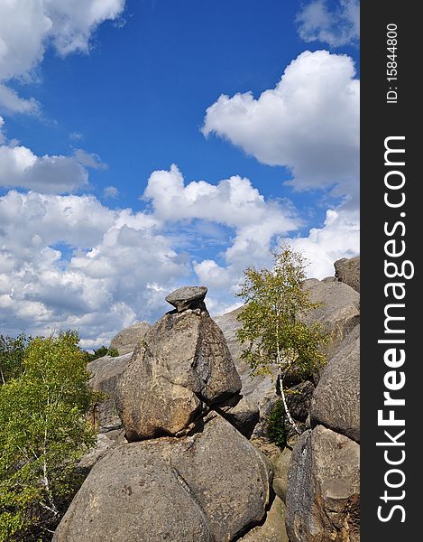 Rocks over wood in an autumn mountain landscape under the dark blue sky. Rocks over wood in an autumn mountain landscape under the dark blue sky