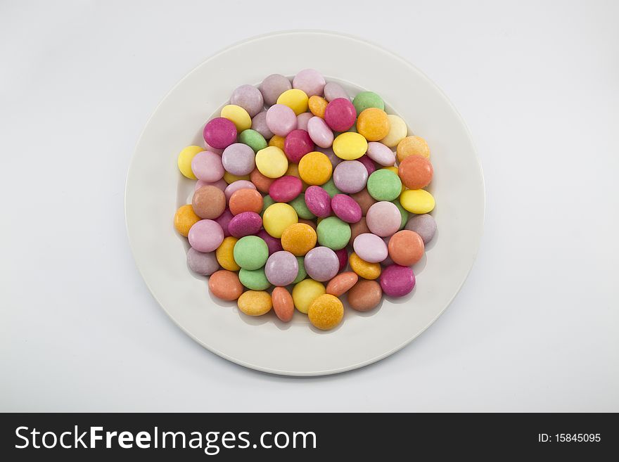 Multi color candy on white dish ,it have yellow green violet pink magenta orange.Put on white dish and white background