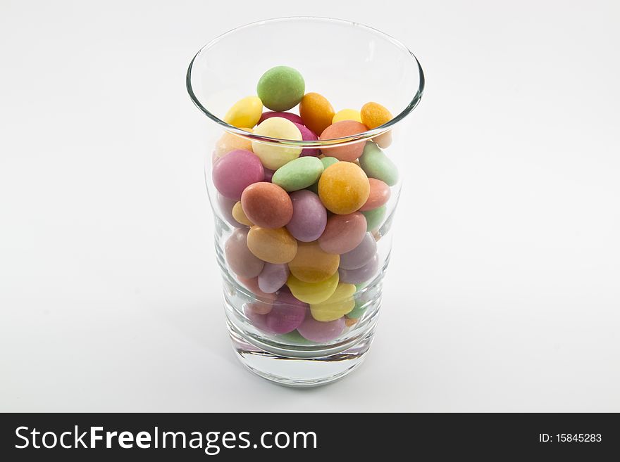 Multi color candy in glass ,it have yellow green violet pink magenta orange.Put in glass and on white background
