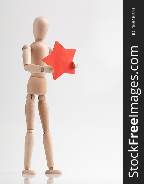 Wooden man figure holding red star shape sticker. Wooden man figure holding red star shape sticker.