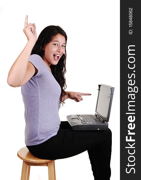 An happy young woman pointing with her finger to her laptop and up in
the air, sitting in black jeans on a chair, for white background. An happy young woman pointing with her finger to her laptop and up in
the air, sitting in black jeans on a chair, for white background.