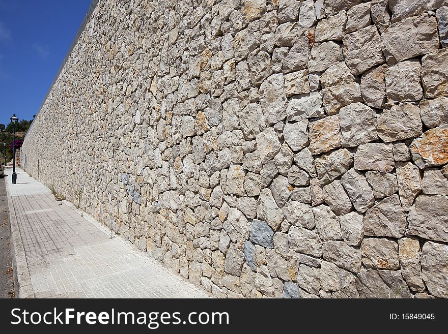 Street along the cobblestone wall in a sunny day