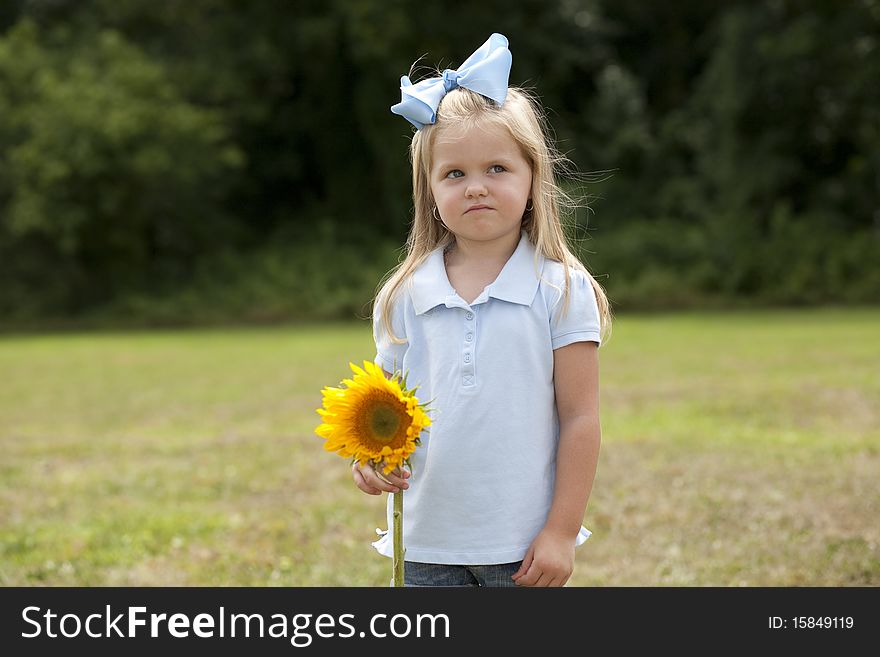 Horizontal image of a cute little girl holding a sunflower. Horizontal image of a cute little girl holding a sunflower