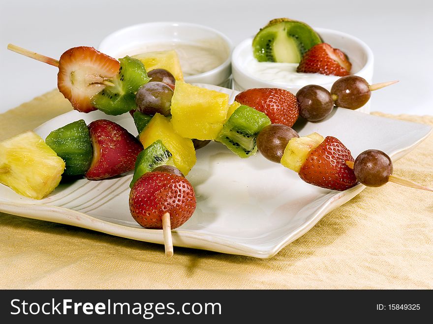 Fruit Kabobs consisting of strawberry,pineapple,grapes, and kiwi,with a yogurt dipping sauce.