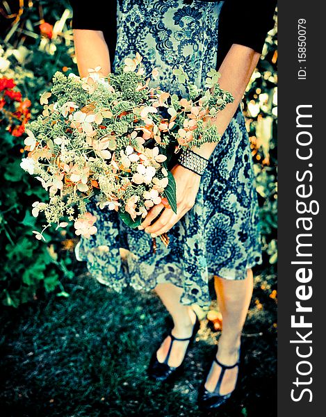 Girl in summer dress holding homemade flower bouquet; trendy colors. Girl in summer dress holding homemade flower bouquet; trendy colors