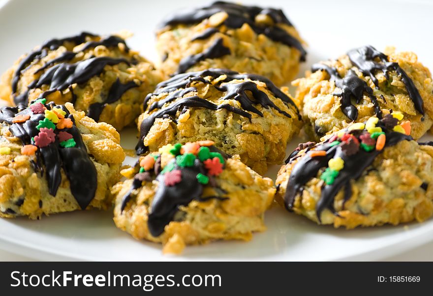 Cornflakes cereal cookies with chocolate sauce and colorful sprinkles