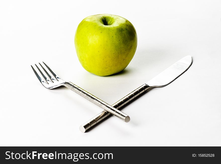 A knife, a fork and an apple on a white background. A knife, a fork and an apple on a white background