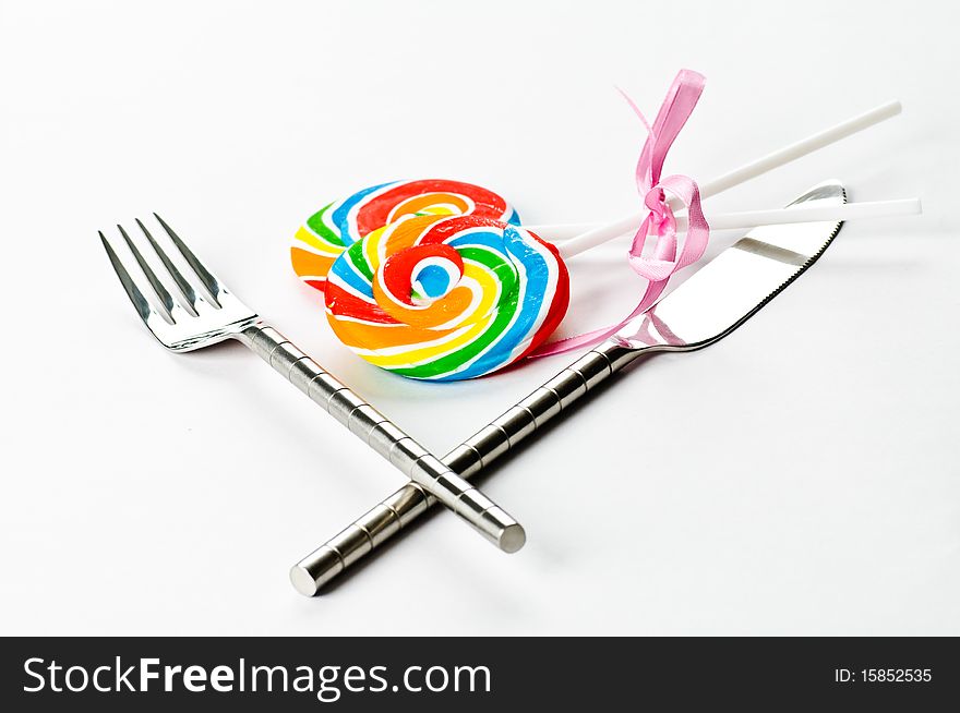 A knife, a fork and an couple of lollipops on a white background. A knife, a fork and an couple of lollipops on a white background