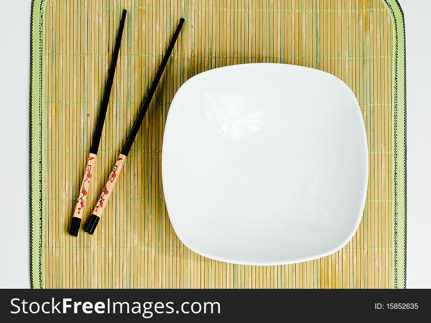 Two chop sticks and a white bowl. Two chop sticks and a white bowl.