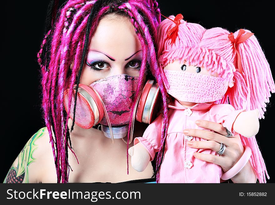 Cosplay young woman in respirator holding a doll over black background. Cosplay young woman in respirator holding a doll over black background.
