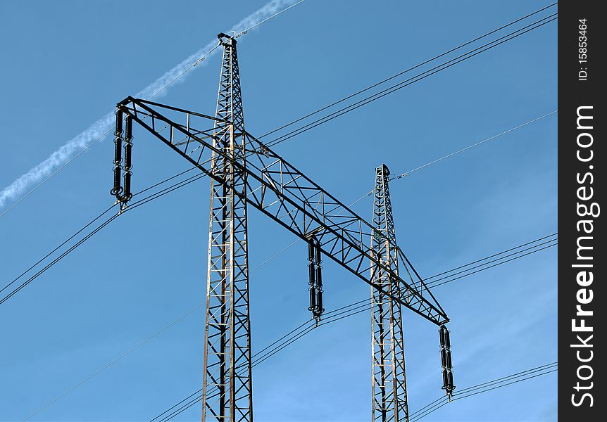 Electricity pylons and cables on the bright blue sky