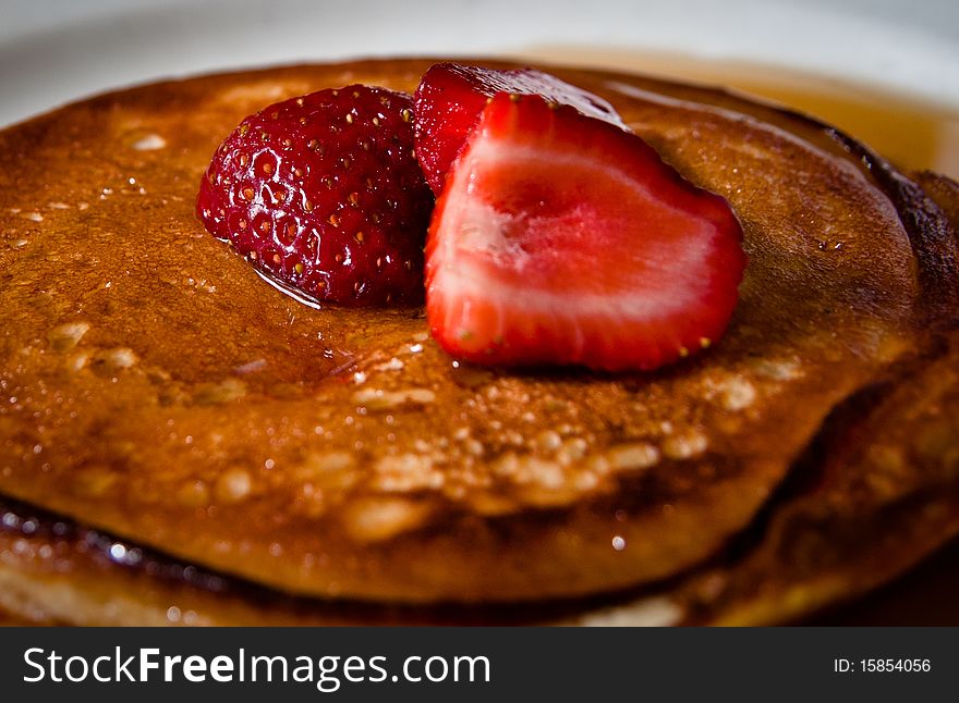 A breakfast of strawberries over pancakes, with syrup. A breakfast of strawberries over pancakes, with syrup.