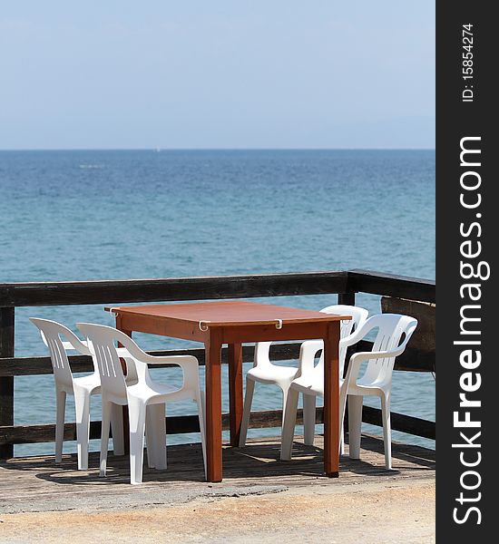 A table and four chairs in sunny and peacefully place by the sea. A table and four chairs in sunny and peacefully place by the sea