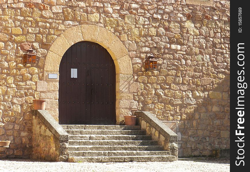 Medieval castle entrance with wooden door and steps in a bright day