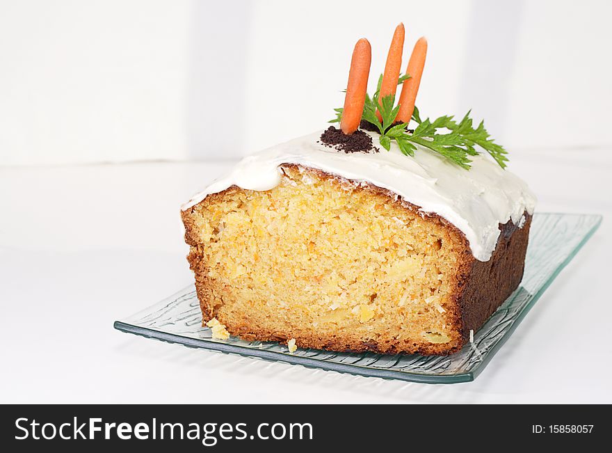Delicious moist carrot cake decorated with chocolate cookie crumbs baby carrots and carrot leaves. Delicious moist carrot cake decorated with chocolate cookie crumbs baby carrots and carrot leaves