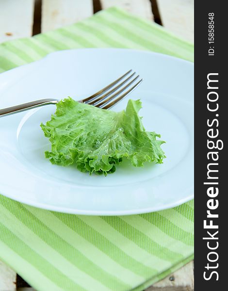 Green leaves on a white plate with a napkin. Green leaves on a white plate with a napkin